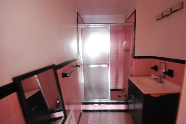 bathroom featuring vanity, a shower with shower door, and tile walls