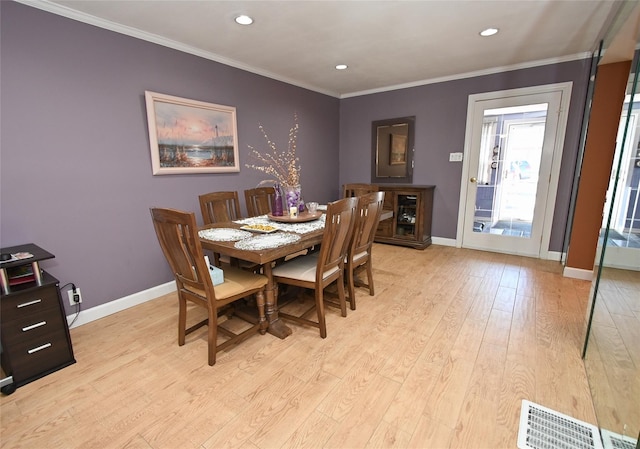 dining room with ornamental molding and light wood-type flooring