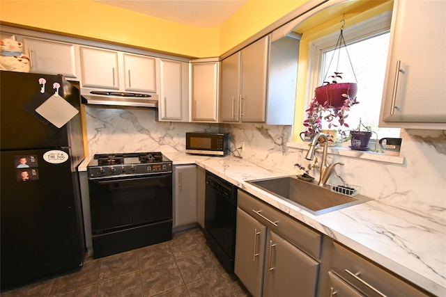 kitchen featuring sink, gray cabinets, black appliances, light stone countertops, and decorative backsplash