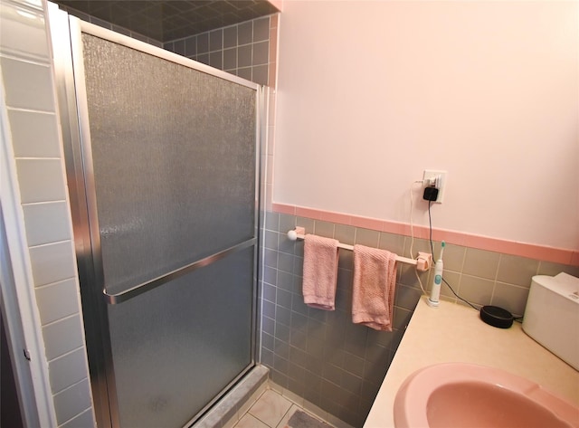 bathroom featuring tile patterned flooring, sink, tile walls, and walk in shower