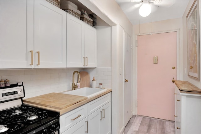 kitchen featuring sink, white cabinetry, tasteful backsplash, light hardwood / wood-style floors, and gas range oven