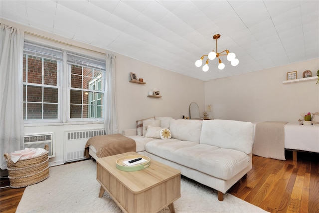 living room featuring radiator, wood-type flooring, a wall mounted AC, and a chandelier