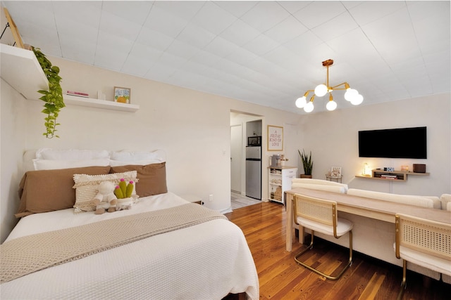 bedroom featuring hardwood / wood-style flooring, a notable chandelier, and stainless steel fridge