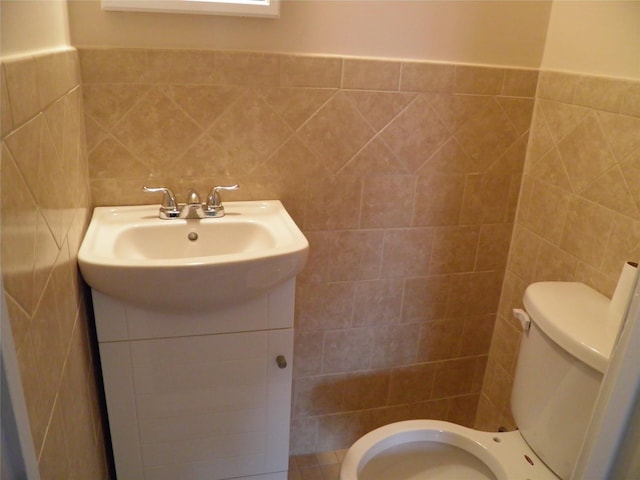 bathroom featuring vanity, tile walls, and toilet