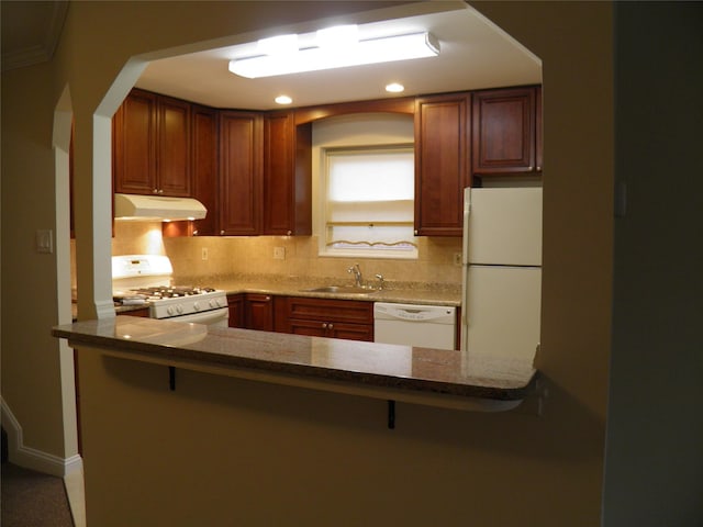 kitchen featuring sink, backsplash, white appliances, and kitchen peninsula