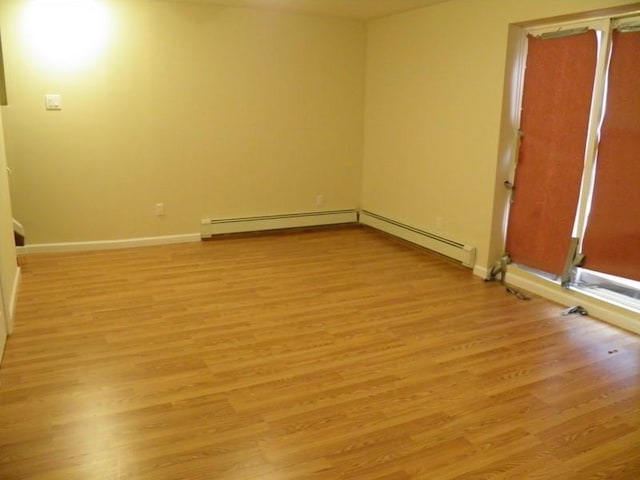 empty room featuring light wood-type flooring and baseboard heating