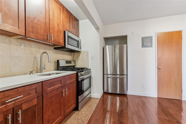 kitchen featuring a sink, baseboards, appliances with stainless steel finishes, backsplash, and dark wood finished floors