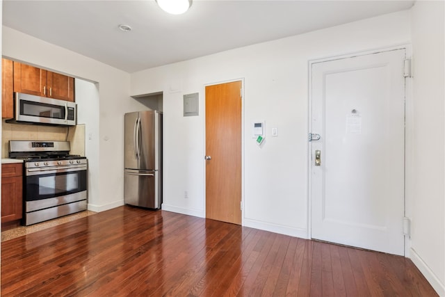 kitchen with appliances with stainless steel finishes, brown cabinetry, and dark wood-type flooring