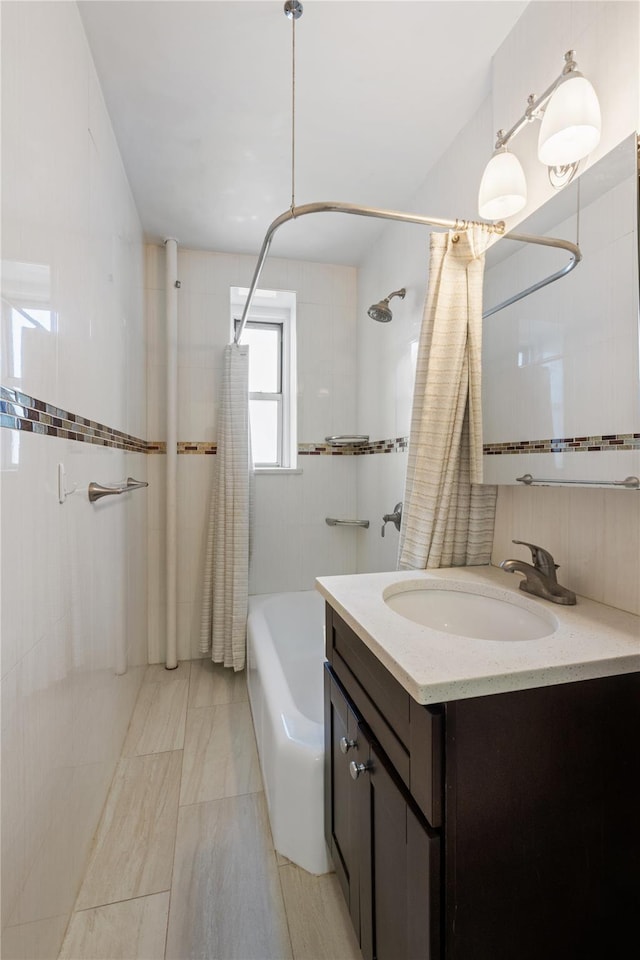 full bath featuring vanity, tile walls, and shower / tub combo with curtain