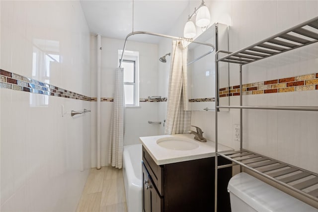 bathroom with shower / bath combination with curtain, vanity, toilet, and tile walls