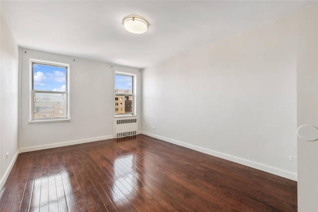 spare room with radiator, baseboards, and dark wood finished floors