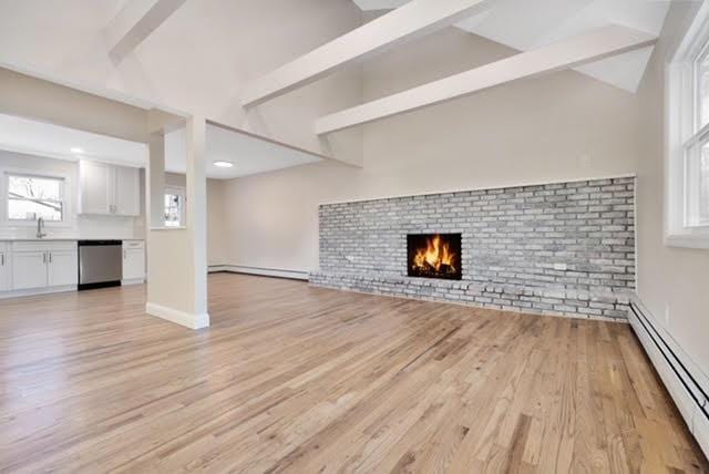 unfurnished living room featuring a fireplace, baseboard heating, and light hardwood / wood-style flooring