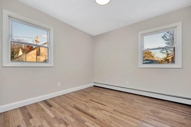 spare room with baseboard heating and light hardwood / wood-style flooring