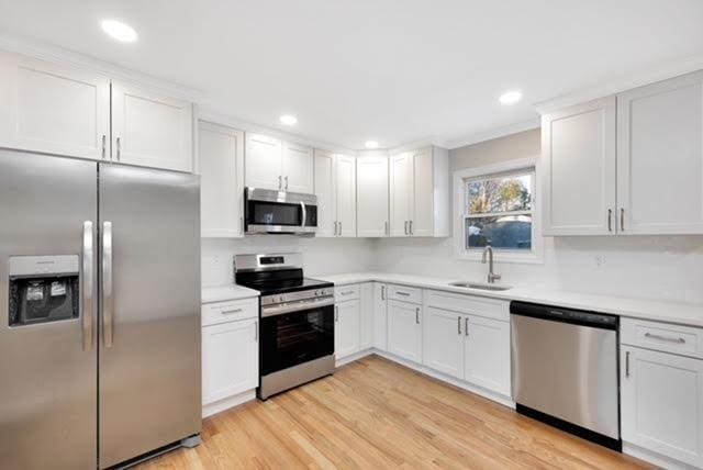 122 Vernon Valley Rd, East Northport, NY 11731 - kitchen featuring light wood-type flooring, a sink, stainless steel appliances, white cabinets, and light countertops