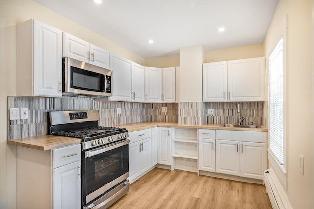 kitchen featuring stainless steel appliances, butcher block countertops, sink, and white cabinets