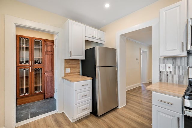 kitchen with backsplash, stainless steel refrigerator, white cabinets, and light wood-type flooring