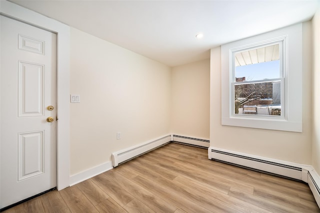 spare room featuring light wood-type flooring and a baseboard heating unit