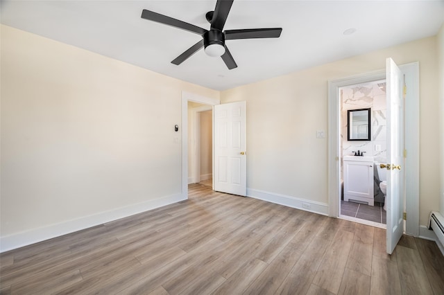 unfurnished bedroom with sink, ensuite bath, ceiling fan, a baseboard radiator, and light wood-type flooring