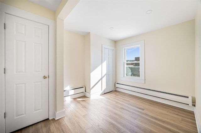 spare room with light wood-type flooring and a baseboard heating unit