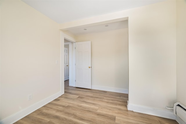 empty room featuring light wood-type flooring and a baseboard heating unit