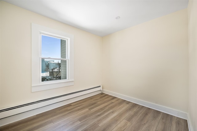 empty room featuring hardwood / wood-style flooring and baseboard heating