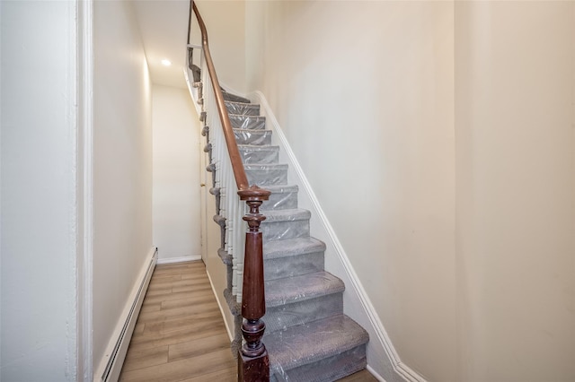 stairway featuring hardwood / wood-style flooring and a baseboard heating unit