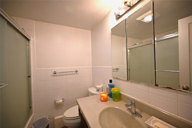 bathroom featuring vanity, toilet, an enclosed shower, and tile walls