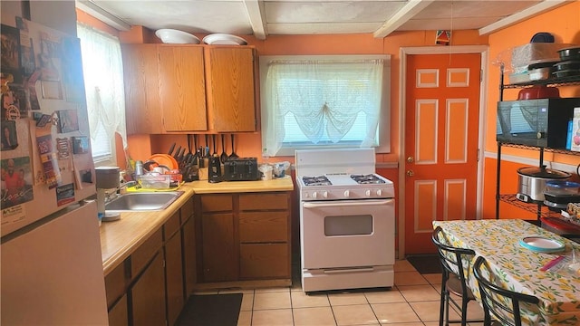 kitchen with light tile patterned flooring, white appliances, and sink