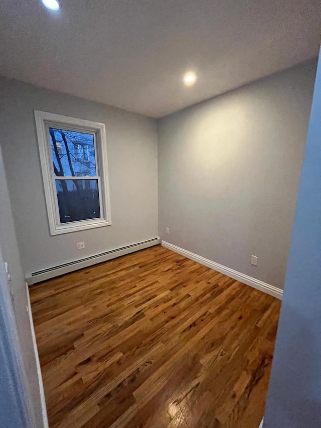 unfurnished room with hardwood / wood-style floors and baseboard heating