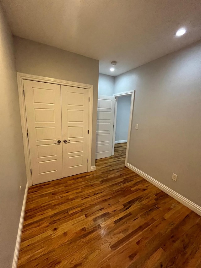 unfurnished bedroom with dark wood-type flooring and a closet