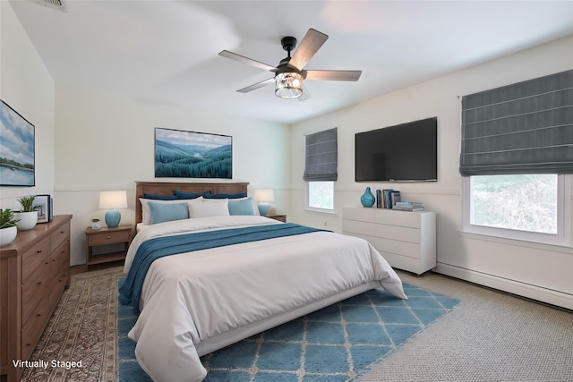 bedroom with ceiling fan, a baseboard radiator, multiple windows, and dark colored carpet