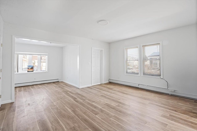 spare room with a baseboard heating unit, a wealth of natural light, and light hardwood / wood-style flooring