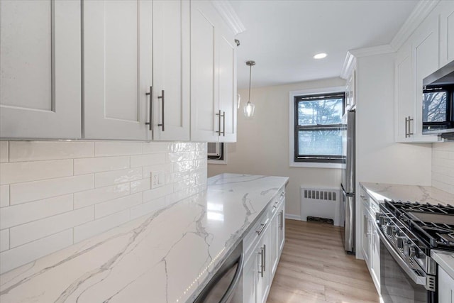 kitchen featuring radiator, pendant lighting, white cabinets, stainless steel appliances, and light stone countertops