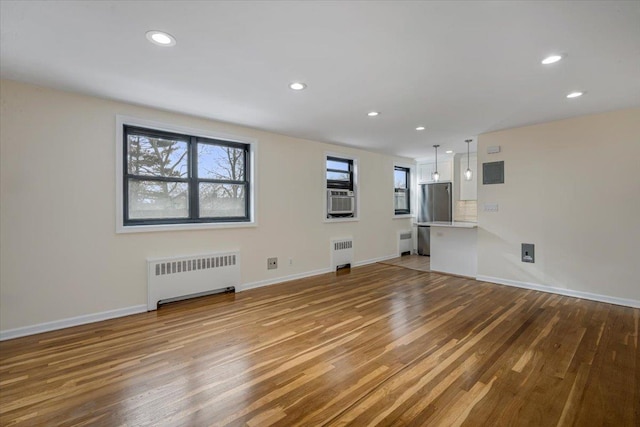 unfurnished living room featuring cooling unit, radiator heating unit, and hardwood / wood-style floors