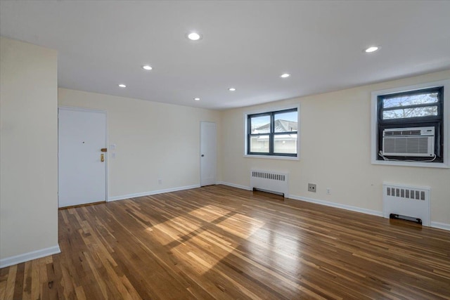 empty room with dark wood-type flooring, radiator heating unit, and cooling unit