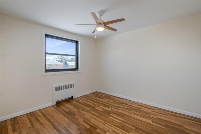 empty room with radiator, hardwood / wood-style floors, and ceiling fan