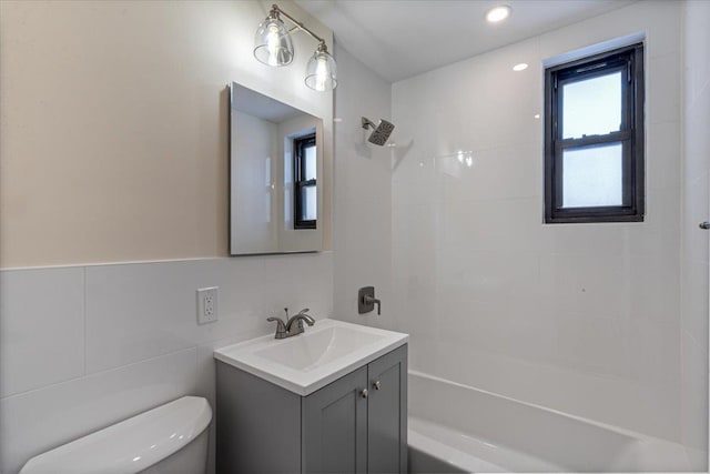 full bathroom with tile walls, decorative backsplash, tiled shower / bath combo, vanity, and toilet