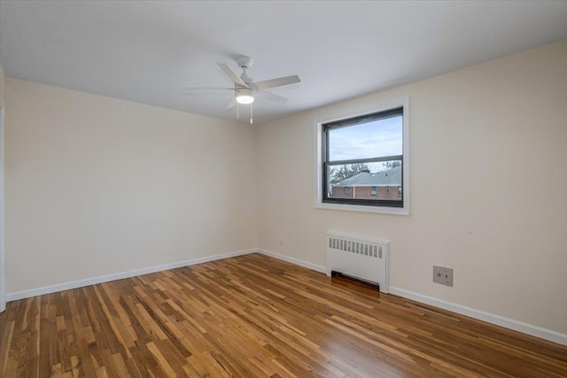 empty room featuring ceiling fan, radiator heating unit, and wood-type flooring