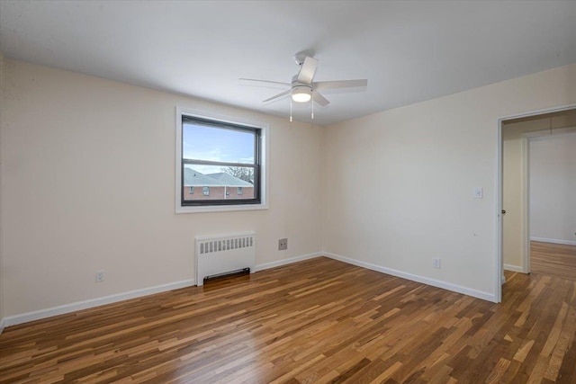 empty room featuring dark wood-type flooring, radiator heating unit, and ceiling fan