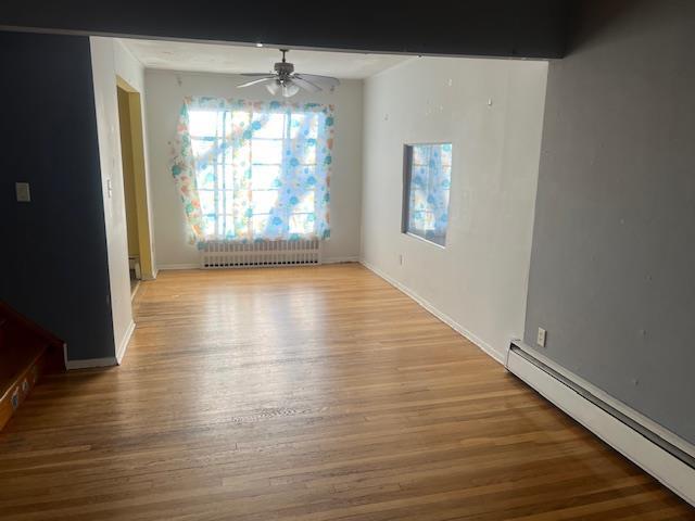 unfurnished dining area featuring light hardwood / wood-style flooring, radiator, a baseboard radiator, and ceiling fan