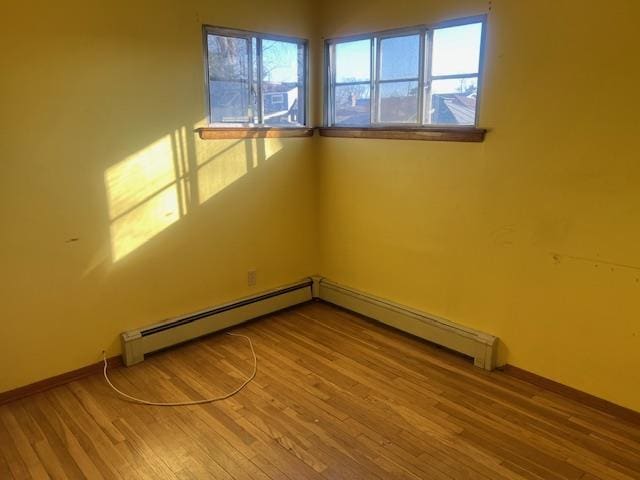 empty room featuring hardwood / wood-style flooring and a baseboard radiator