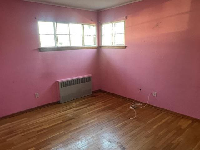 spare room featuring hardwood / wood-style flooring, radiator, and a wealth of natural light