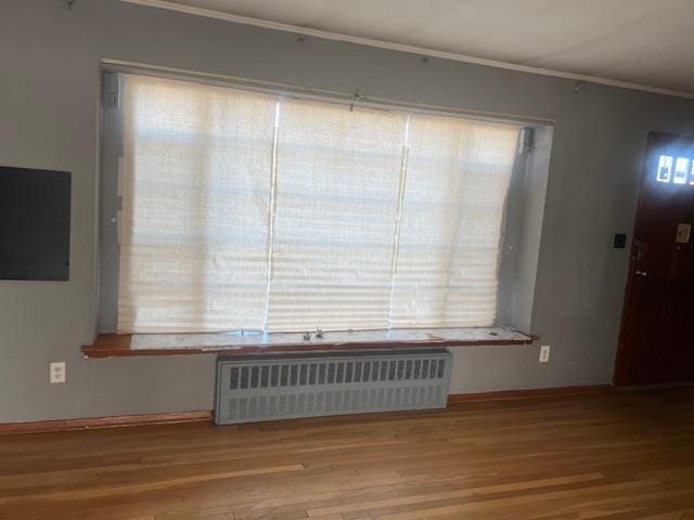 interior space with wood-type flooring and radiator heating unit