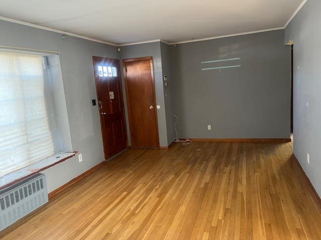 entryway featuring crown molding, radiator heating unit, and light hardwood / wood-style flooring