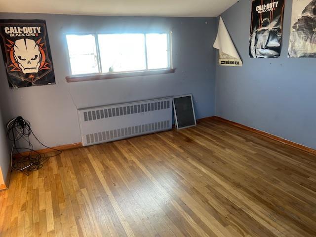 spare room featuring radiator and hardwood / wood-style flooring