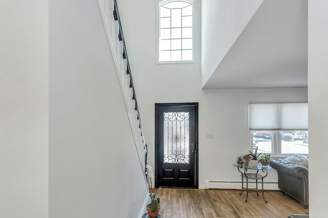 foyer entrance with hardwood / wood-style flooring, ornamental molding, and a baseboard heating unit