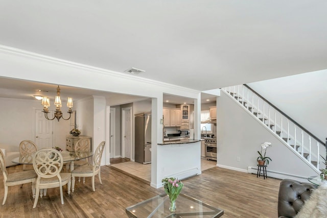 living room with ornamental molding, a chandelier, baseboard heating, and light hardwood / wood-style flooring