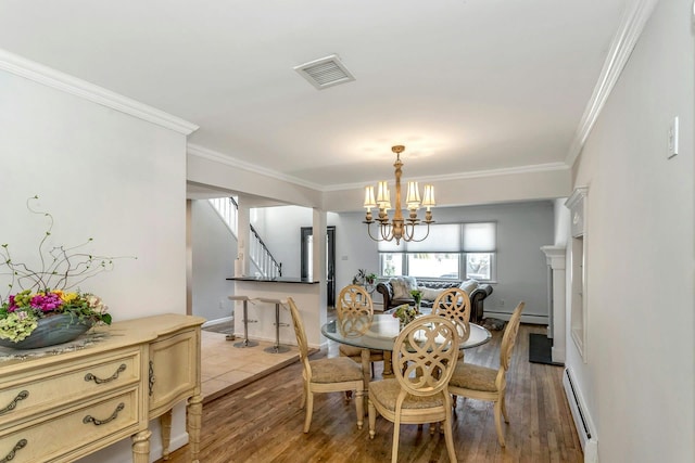 dining area with ornamental molding, a baseboard heating unit, an inviting chandelier, and light wood-type flooring