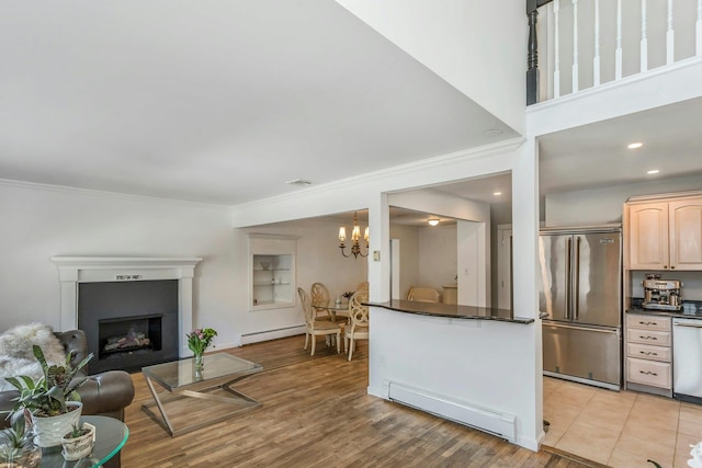 kitchen with stainless steel appliances, a notable chandelier, light brown cabinetry, and baseboard heating