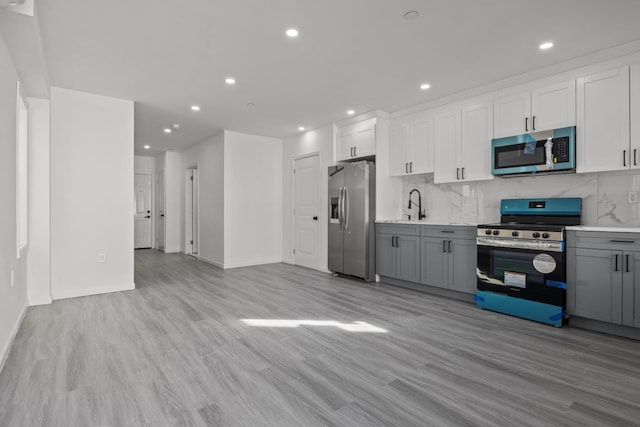 kitchen with sink, gray cabinetry, backsplash, stainless steel appliances, and white cabinets